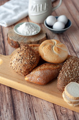 Various baked breads and rolls on wooden table