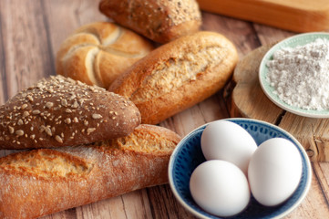 Various baked breads and rolls on wooden table
