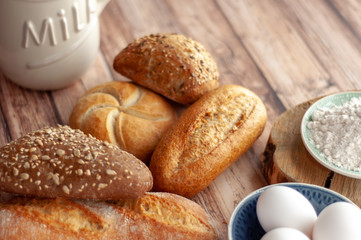 Various baked breads and rolls on wooden table