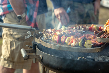 Grill party with friends. Talking guys at the grill. Shallow depth of field.