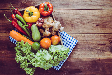 Many kind of vegetable inside and outside wood tray on wood background, for cooking and kitchen concept.