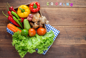 Many kind of vegetable inside and outside wood tray on wood background, for cooking and kitchen concept.