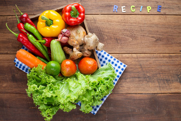 Many kind of vegetable inside and outside wood tray on wood background, for cooking and kitchen concept.