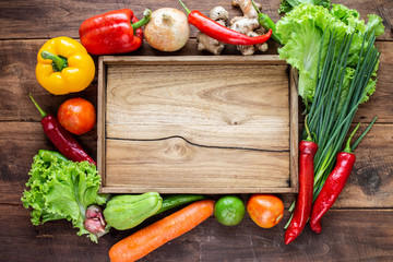 Many kind of vegetable inside and outside wood tray on wood background, for cooking and kitchen concept.