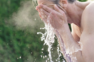Portrait of topless man splashing face with water