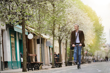 Fototapeta na wymiar Businessman on daily commute riding micro scooter