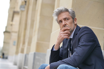 Fototapeta premium Businessman sitting outdoors looking stressed