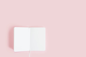 unfolded notebook with white sheets on a pink background