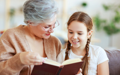 happy family grandmother reading to granddaughter book at home