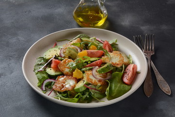 Middle Eastern grilled halloumi cheese salad with avocado, oranges, cherry tomatoes, red onion, arugula beet leaves.