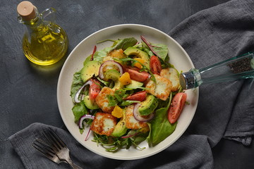 Middle Eastern grilled halloumi cheese salad with avocado, oranges, cherry tomatoes, red onion, arugula beet leaves.
