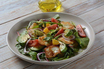 Middle Eastern grilled halloumi cheese salad with avocado, oranges, cherry tomatoes, red onion, arugula beet leaves.