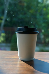 take away cup for hot coffee drink put on wooden table in cafe