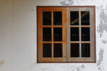 old glass window with wooden frame on weathered wall