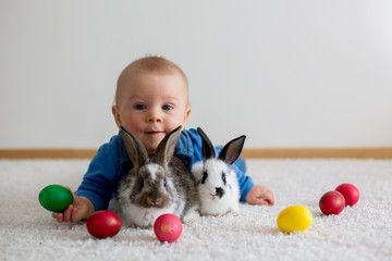 Fototapeta na wymiar Little toddler child, baby boy, playing with bunnies and easter eggs at home