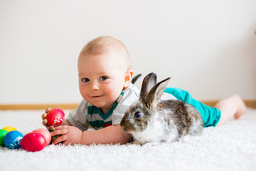 Little toddler child, baby boy, playing with bunnies and easter eggs at home