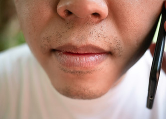 Fototapeta premium Close-up mouth picture of Asian men with using smart phone and wearing a white shirt.
