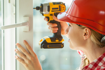 Woman using drill on window