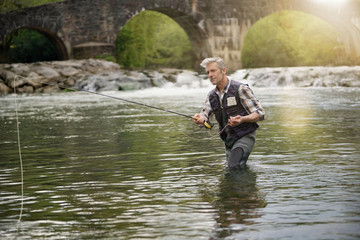 Mature man fly fishing in beautiful river