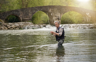 Mature man fly fishing in beautiful river