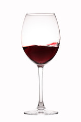 Red wine splashes in a glass on white background