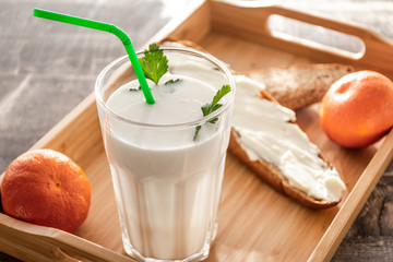 Cooking base kitchen concept. Morning milk glass. Buttermilk dairy drink breakfast on wooden desk. Tangerine, bread, butter.
