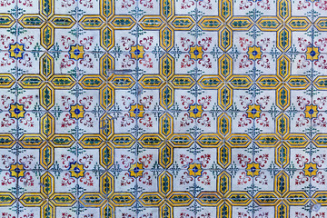 a fragment of the outer wall of a house in Lisbon decorated with ceramic tiles with a beautiful geometric pattern.