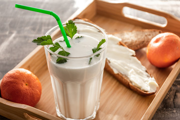 Morning milk glass. Buttermilk dairy drink breakfast on wooden desk. Tangerine, bread, butter.