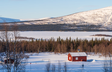 Red house of Aktse in the snow, with view toward National Park Sarek. Lapland, Sweden.