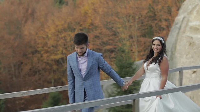 Groom with bride on a bringe near mountain hills in the forest. Wedding couple