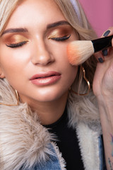 Obraz premium A make-up artist makes a make-up for a smaptic blonde girl