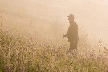 man with a camera in the fog on a summer field. Summer early morning.