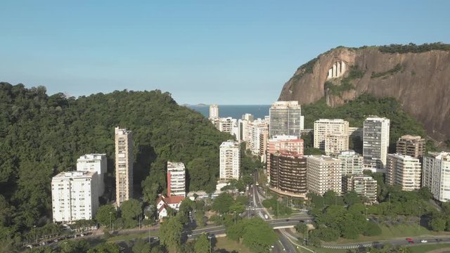 Slow aerial movement forward and downward with view of high rise residential buildings with a mountain behind revealing a highway intersection with traffic