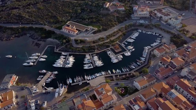 Aerial of a pretty village in Sardinia, Italy. Sunrise on the coast, parking yachts, mountains in the background