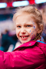staged photo. girl blonde on the podium. there is an inscription on the cheek. she is glad that the team is winning. there is toning.