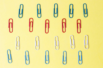 Multicolored paper clips on a yellow background, office concept