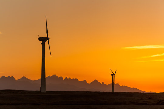 Big wind turbines in the desert against mountains