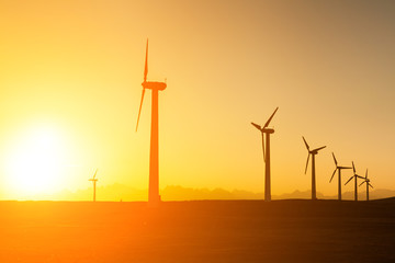 Obraz premium Big wind turbines in the desert at sunset background