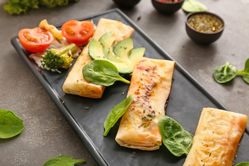 Plate with tasty fried spring rolls on grey table