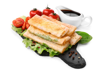 Slate plate with tasty fried spring rolls on white background