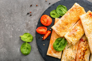 Slate plate with tasty fried spring rolls on grey background