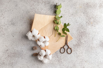 Cotton flowers with envelope and scissors on grey background