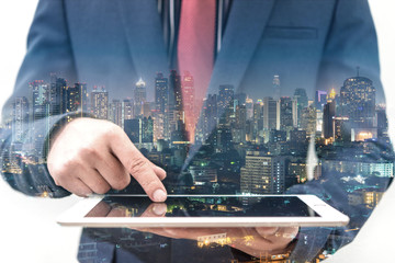 double exposure of businessman using tablet at meeting with blur city night