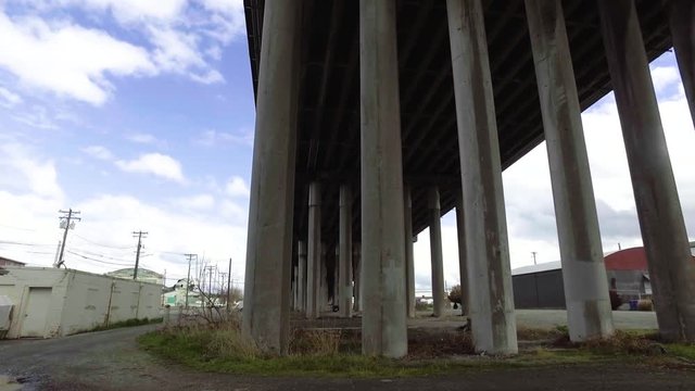 Passing under a concrete overpass from left to right on a partly cloudy spring day after a brief rain