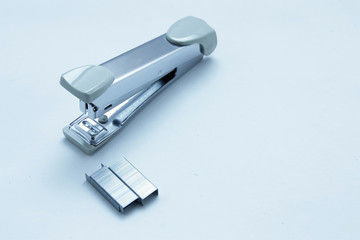 Stapler and staple on plain white background