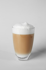 Glass of tasty frappe coffee on light background