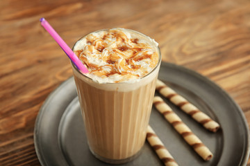 Tray with glass of tasty frappe coffee on wooden table