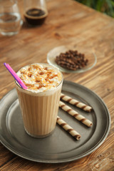 Tray with glass of tasty frappe coffee on wooden table