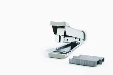Stapler and staple on plain white background