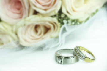 Wedding ring for groom and bride with soft yellow pink roses background.